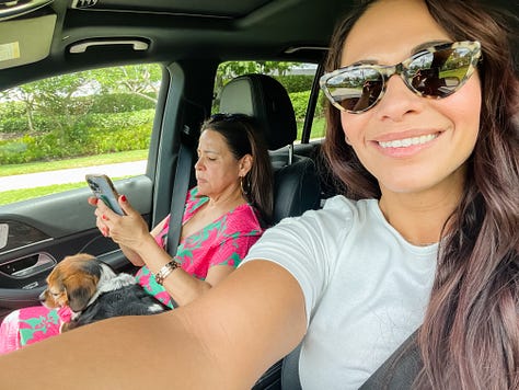 Photo of two women with a mountain landscape in the background; selfie photo of two women and a dog in a car; Selfie photo of woman with a dog sitting in a car; selfie photo of a family of four adults: brother and sister, and mom and dad; photo of two hands in shape of a heart in foreground and a mixing bowl with banana bread mix behind and below it; a baked banana bread in a glass loaf pan atop a stove; a photo of a carrot cake with glazed frosting and chopped pecans sprinkled on top; photo of a garden plot of blossoming flowers and vegetables and a placard in front that reads 'community garden'; photo of dog on couch curled up next to photographer's legs.