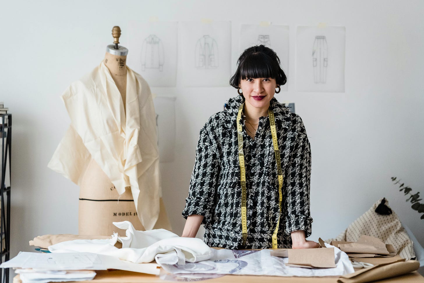 Photo by Michael Burrows: https://www.pexels.com/photo/cheerful-asian-female-dressmaker-standing-at-table-during-work-in-atelier-7148002/