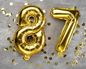 Gold metallic party balloons in the shape of the number 87. Gold metallic party balloons in the shape of the number 87.