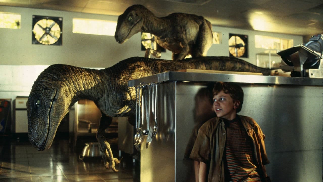 Two velociraptors hunt a boy hiding in a kitchen in Jurassic Park, illustrating coordinated pack behavior. Two velociraptors hunt a boy hiding in a kitchen in Jurassic Park, illustrating coordinated pack behavior.