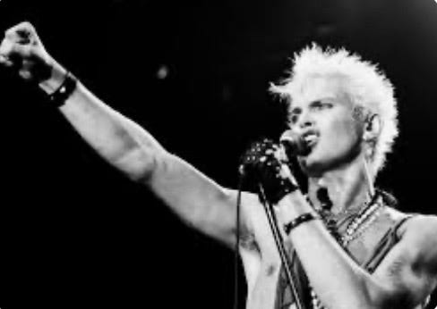 A person with white hair holding a microphone

Description automatically generated