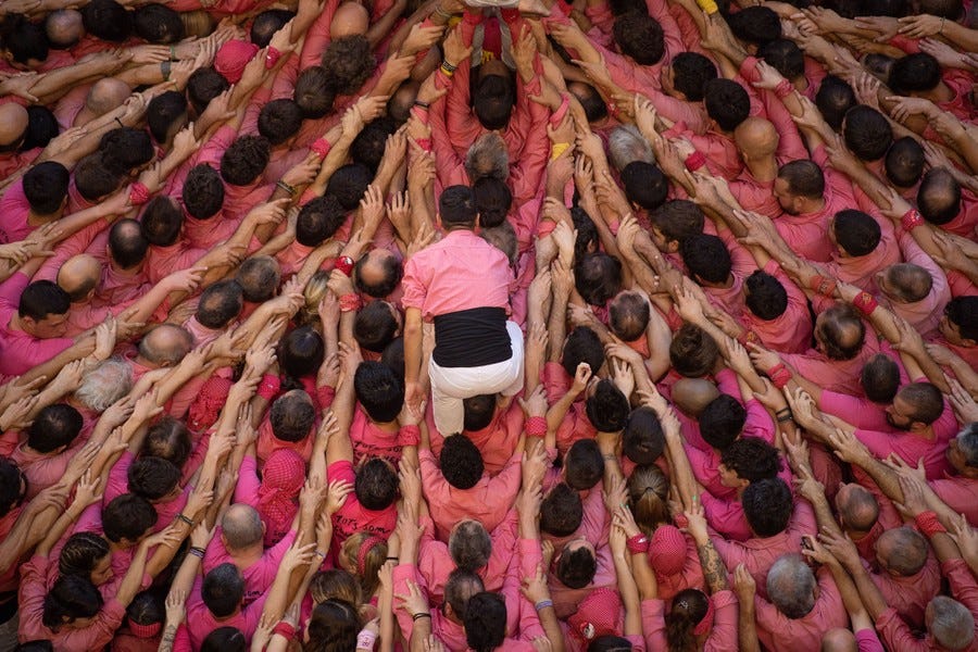 A person walks on the shoulders of a crowd of people, all of them with arms outstretched to support those in front of them.