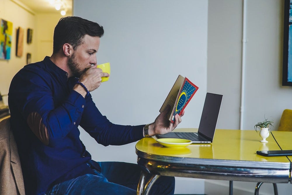 person reading book while drinking beverage person reading book while drinking beverage