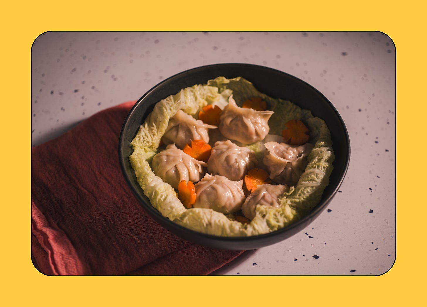 A black bowl containing steamed Lion's Head dumplings sits on a speckled counter
