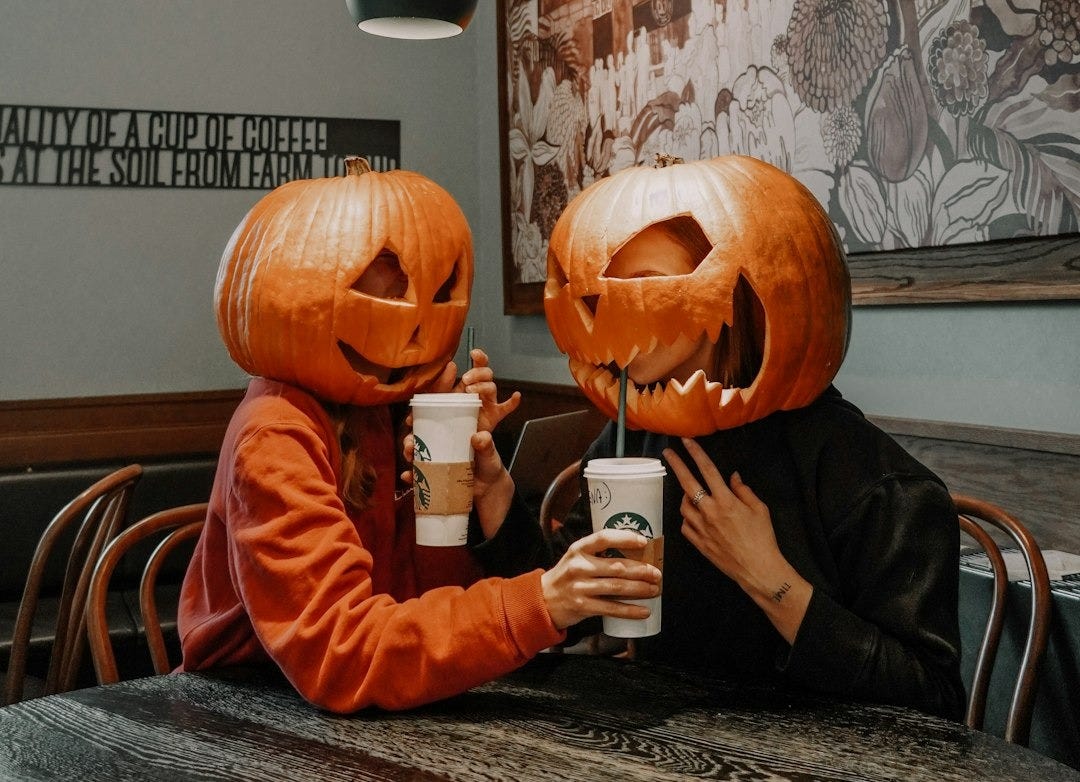 two people sitting at a table with pumpkin heads on their heads two people sitting at a table with pumpkin heads on their heads