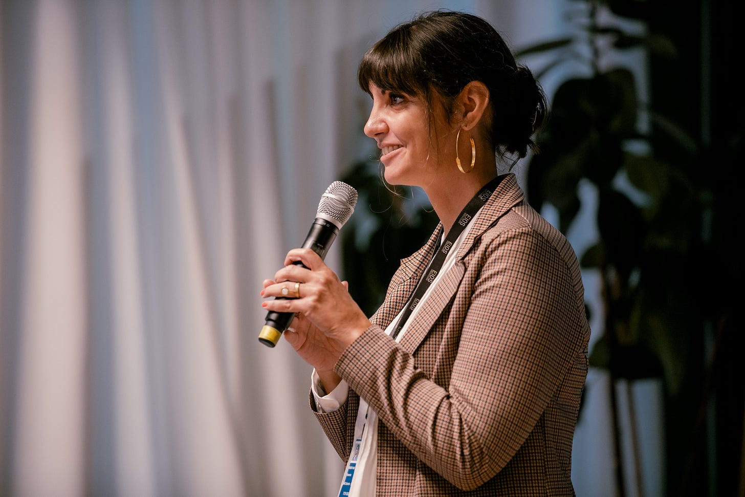 Yasmin is standing on a stage and holding a microphone.