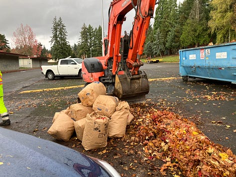 Subara hatch open with bags of leaves, food drive and leave drop-off sign, tractor lift