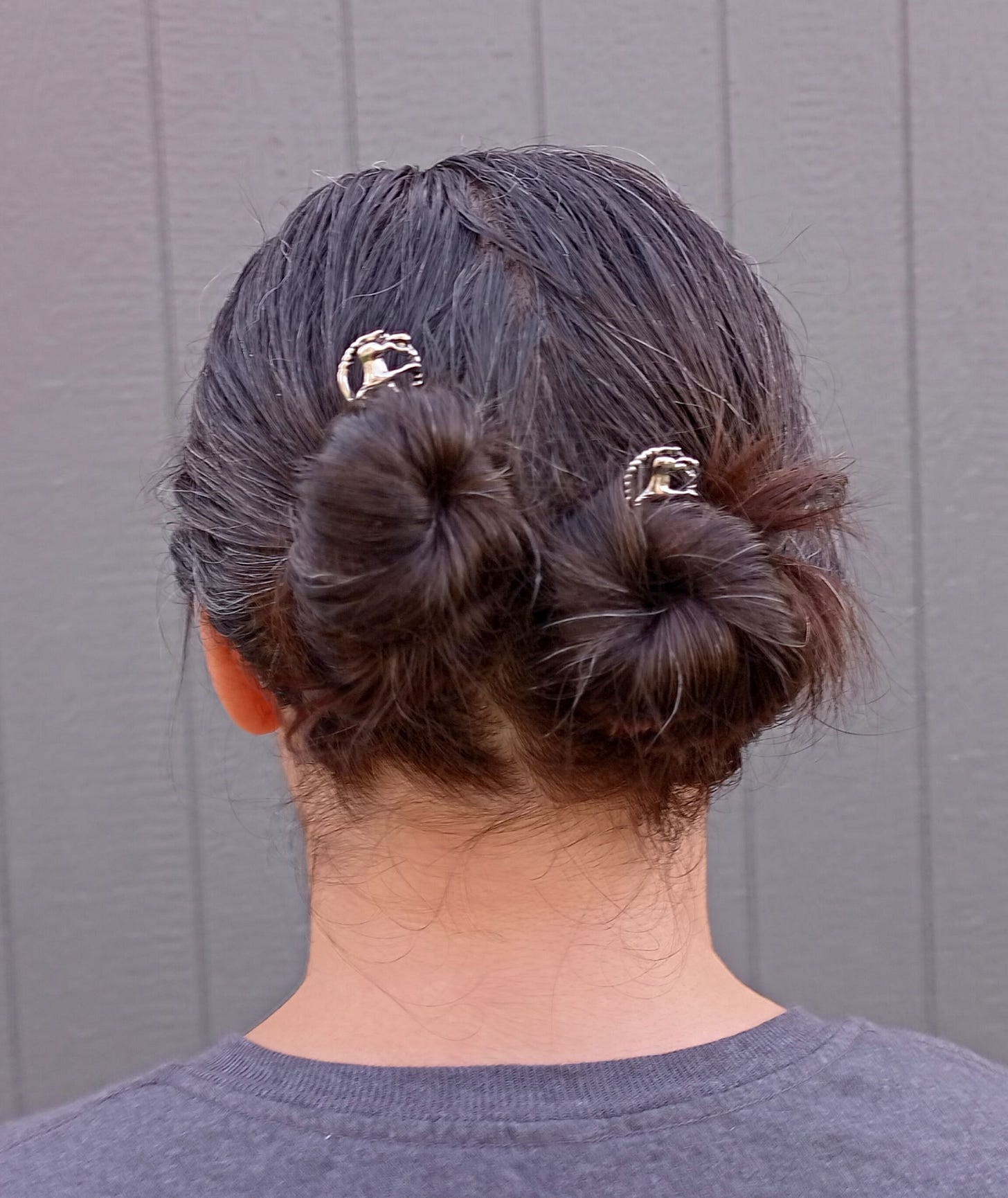 Woman with brown hair in pigtail buns with silver horse bobby pins