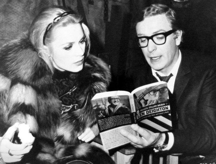 This may contain: an old black and white photo of a man reading a book to a woman in a fur coat This may contain: an old black and white photo of a man reading a book to a woman in a fur coat