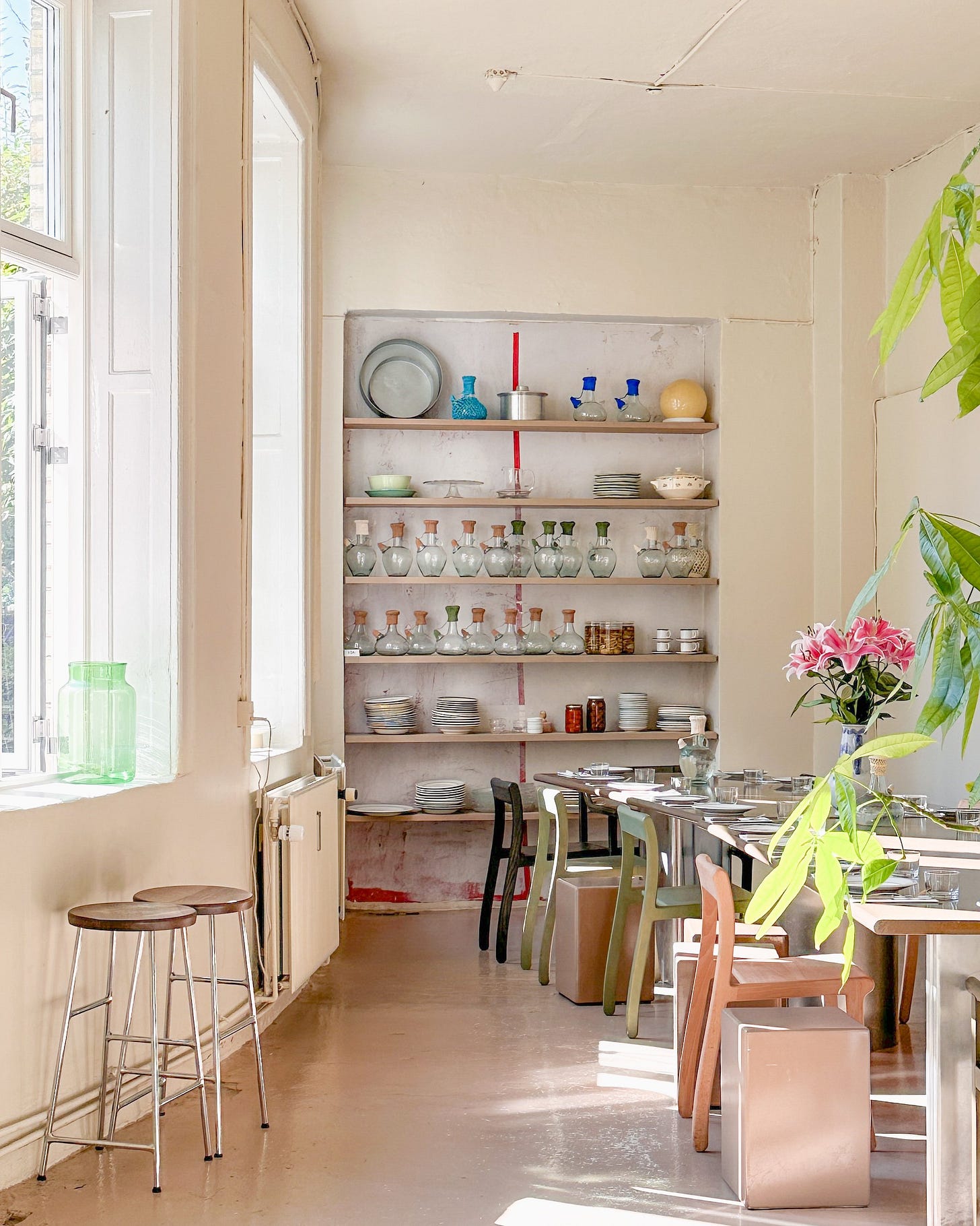 Interior of BeitSalma with a long dining table set with plates, glasses, and a floral centerpiece. Enjoy Lebanese restaurant ambiance with Scandinavian minimalism at BeitSalma in Copenhagen.