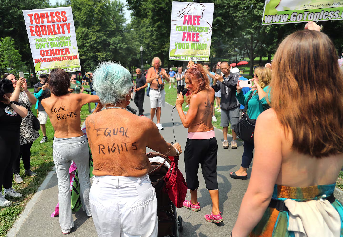 Topless women with “Equal Rights” written on their backs participate in a protest at Boston Common. They are surrounded by supporters, some holding signs that read “TOPLESS EQUALITY” and “FREE YOUR BREASTS! FREE YOUR MIND!” Topless women with “Equal Rights” written on their backs participate in a protest at Boston Common. They are surrounded by supporters, some holding signs that read “TOPLESS EQUALITY” and “FREE YOUR BREASTS! FREE YOUR MIND!”