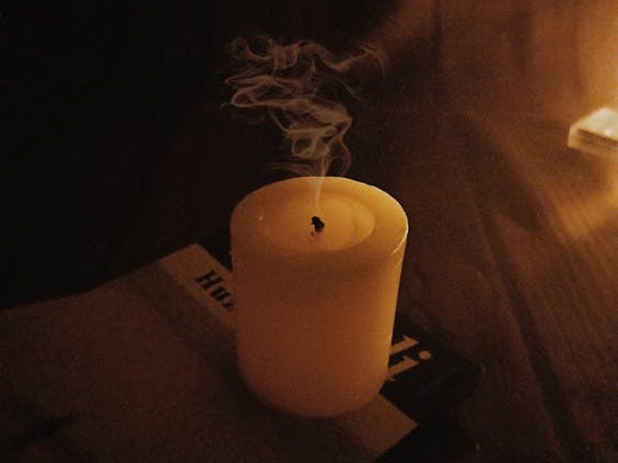 Free A blown-out candle with smoke curling in dim lighting, emphasizing a calm ambiance. Stock Photo