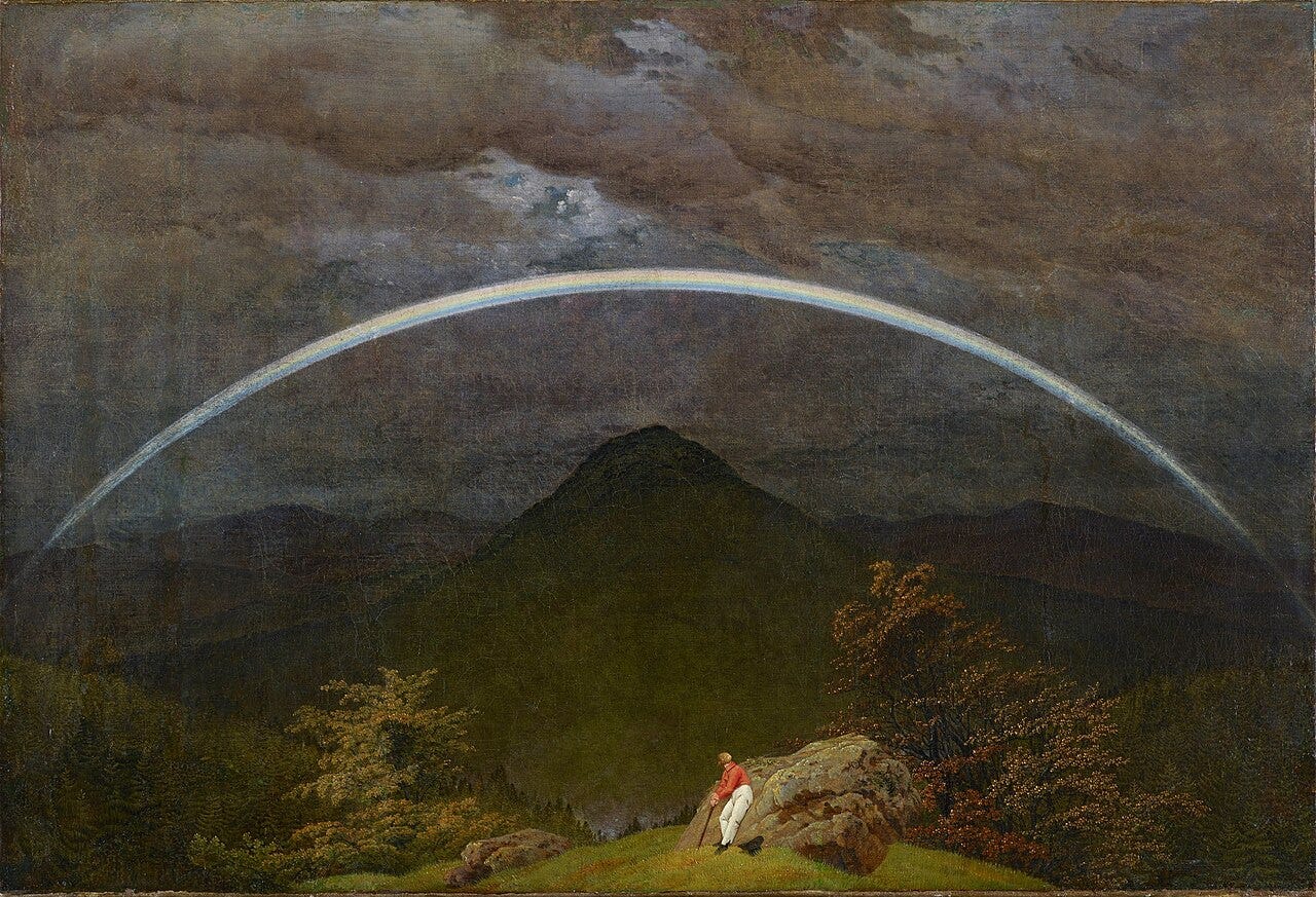 A lone man rests against a rock in dark mountains beneath a pale glowing rainbow at dusk A lone man rests against a rock in dark mountains beneath a pale glowing rainbow at dusk