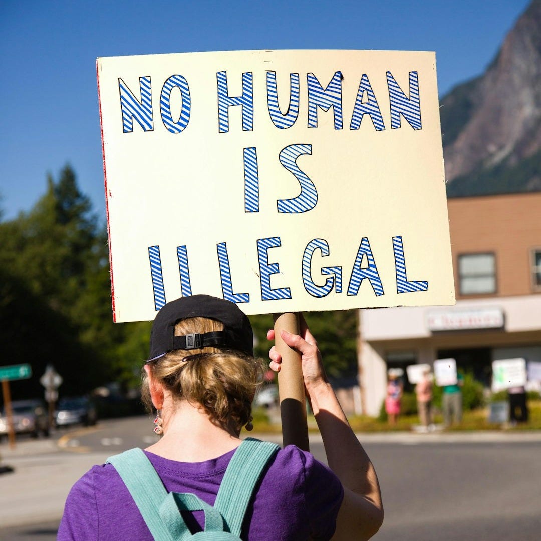 Person holds sign that says "no human is illegal"