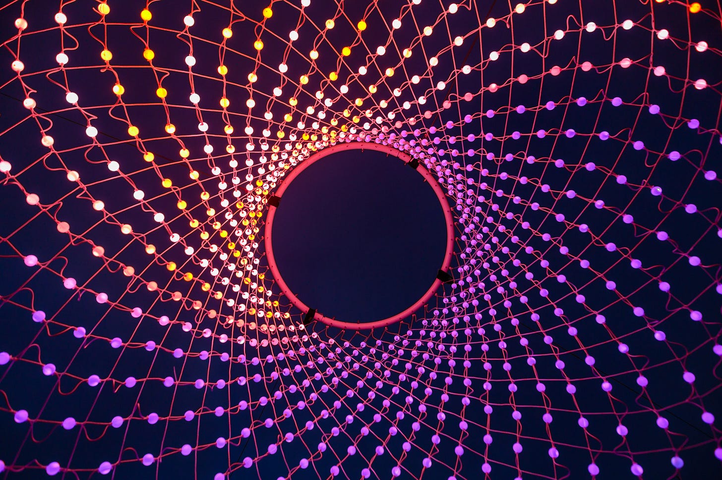 A circle of colourful LED lights against a blue sky.