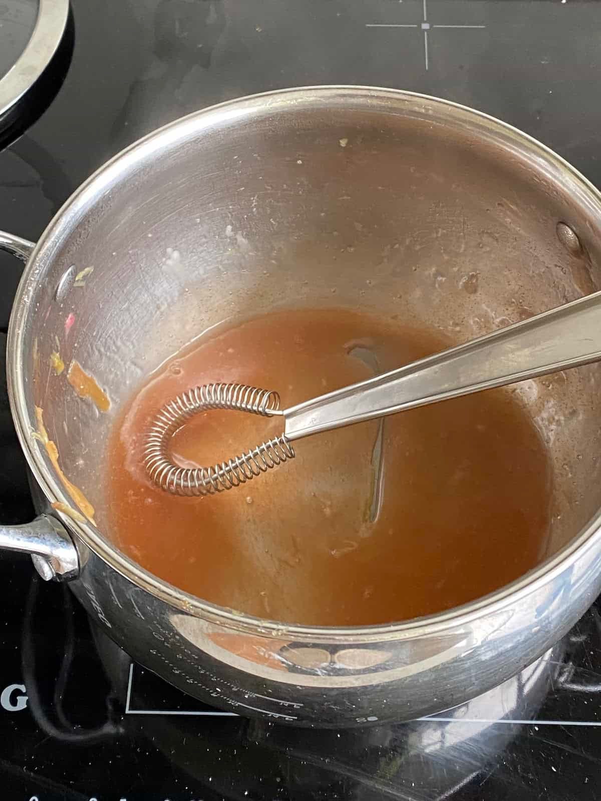 Rhubarb syrup in a small pan.