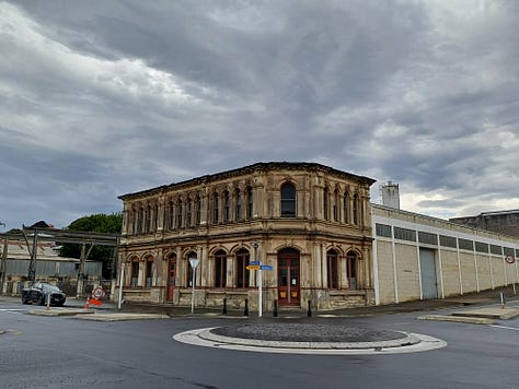 A series of stone buildings, created in a variety of styles, from fairly plain and study to huge and ornate. All of the buildings are made from or incorporate creamy limestone, some soot-blackened or weathered. On the right top is a locomotive engine cab with a large screw mounted at the front, located to indicate that it has just burst up out of the ground. The bottom right features a whitestone bridge fording a stream, over which the main street is laid.