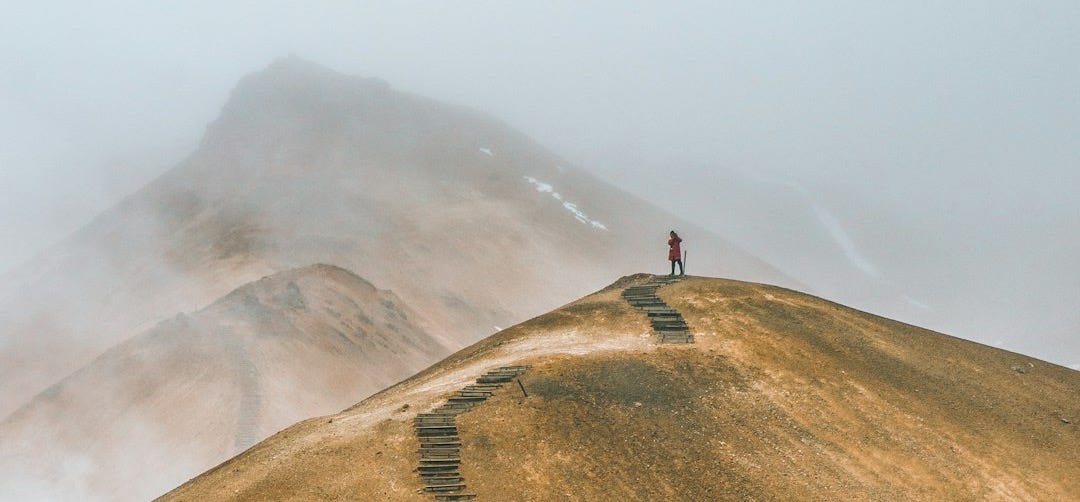 man on top brown hill