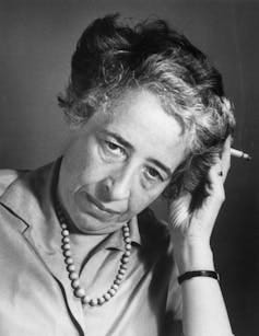 A gray-haired woman with a cigarette, looking thoughtful.