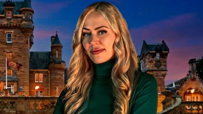 A woman with long blonde hair, wearing a green polo neck top, smiles to camera, set against the backdrop of castle at night A woman with long blonde hair, wearing a green polo neck top, smiles to camera, set against the backdrop of castle at night