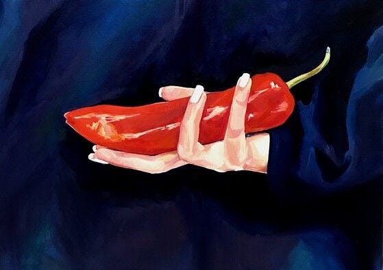 A hand with pale skin and manicured nails gently cradles a long red chili pepper against a dark, silky blue background. The gesture is soft but suggestive, evoking intimacy, power, and restraint.