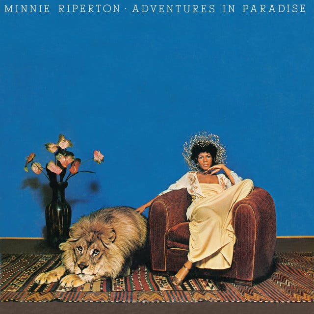 Adventures in Paradise is the third studio album by Minnie Riperton issued in May 1975 by Epic Records. On the album cover photographed by Kenneth McGowan, Minnie is seen sitting serenely next to a lion with baby’s breath in her afro, in front of an aqua blue background. Adventures in Paradise is the third studio album by Minnie Riperton issued in May 1975 by Epic Records. On the album cover photographed by Kenneth McGowan, Minnie is seen sitting serenely next to a lion with baby’s breath in her afro, in front of an aqua blue background.
