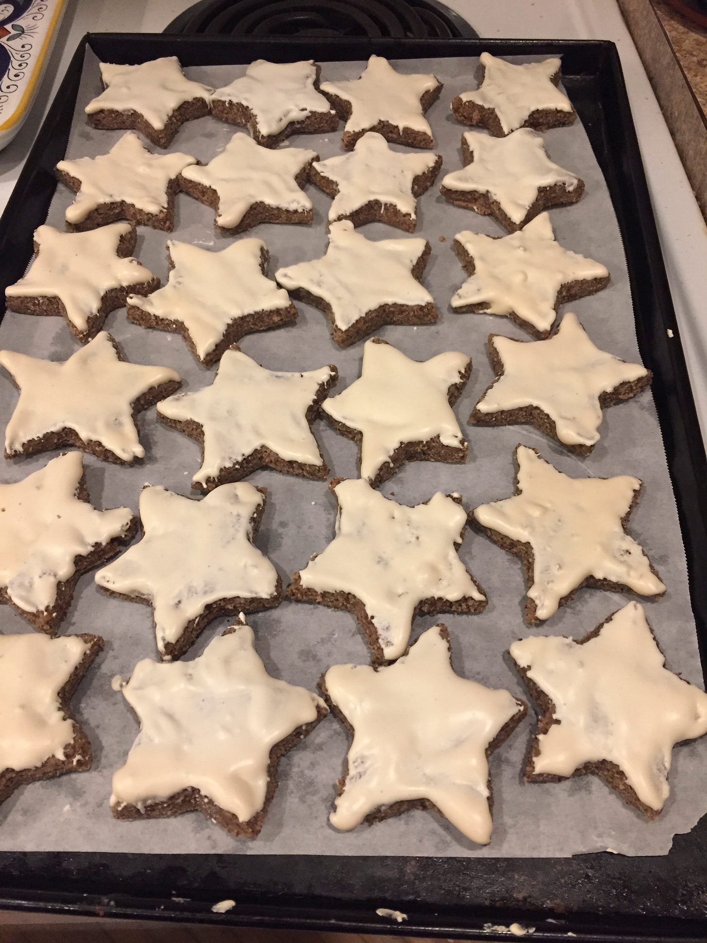 A baking pan full of zimtsterne, resting on top of the stove.