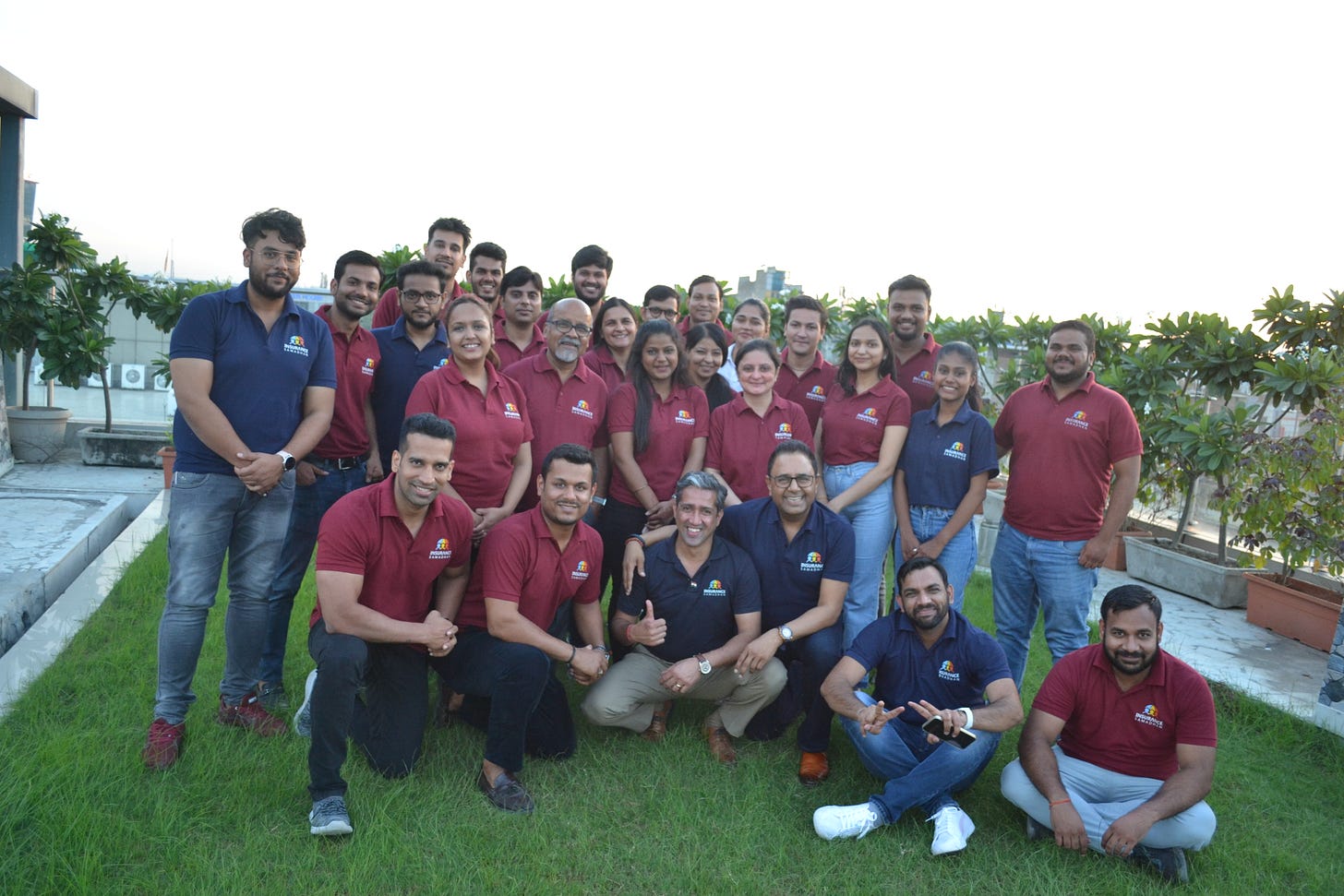 A group of people, working in the same team, standing outdoors, to take a photo together