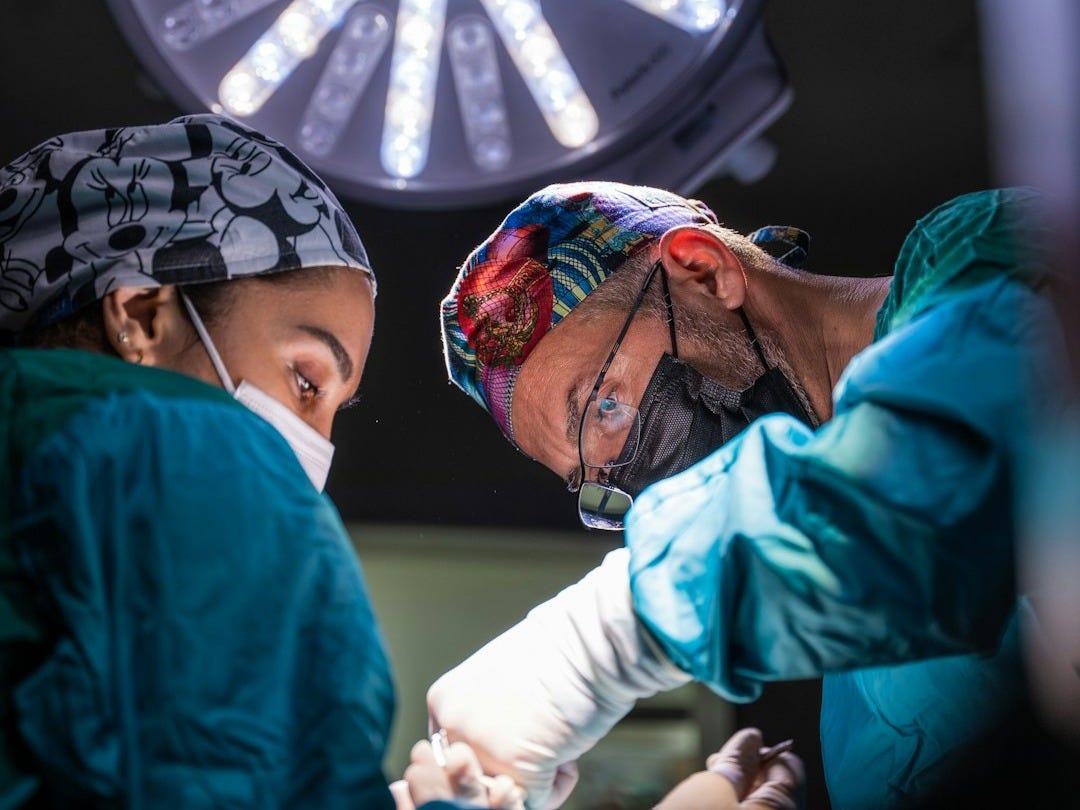 two surgeons performing surgery on a patient in a hospital two surgeons performing surgery on a patient in a hospital