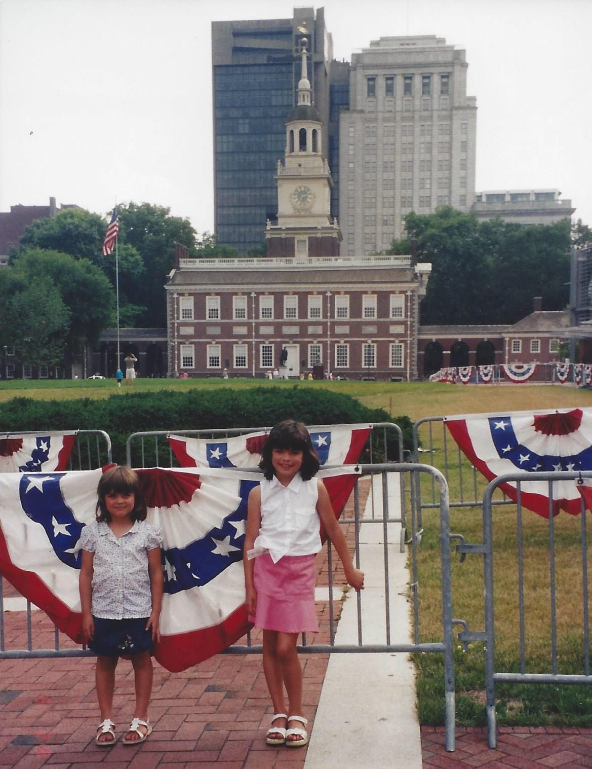 Two young girls stand on Independence Mall, with Independence Hall in the background