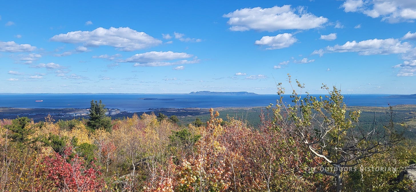 The distinct profile of the Sleeping Giant peninsula visible across the water in the distance, framed by the rocky foreground of the summit.