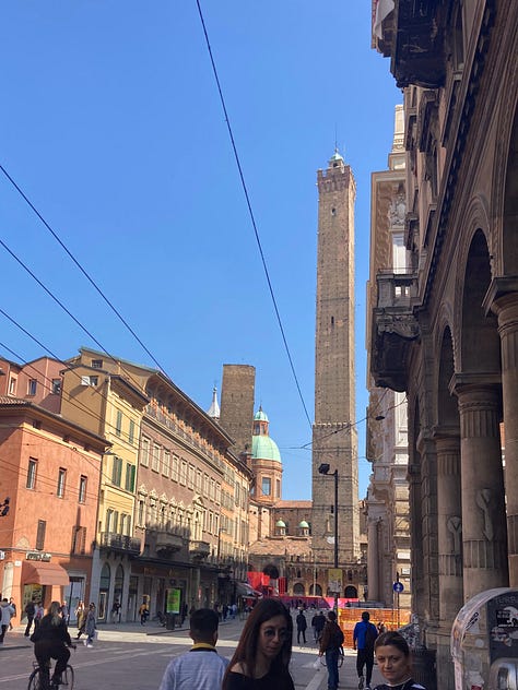 Photographs of views from the street in Bologna showing historic towers and a verdant florist.