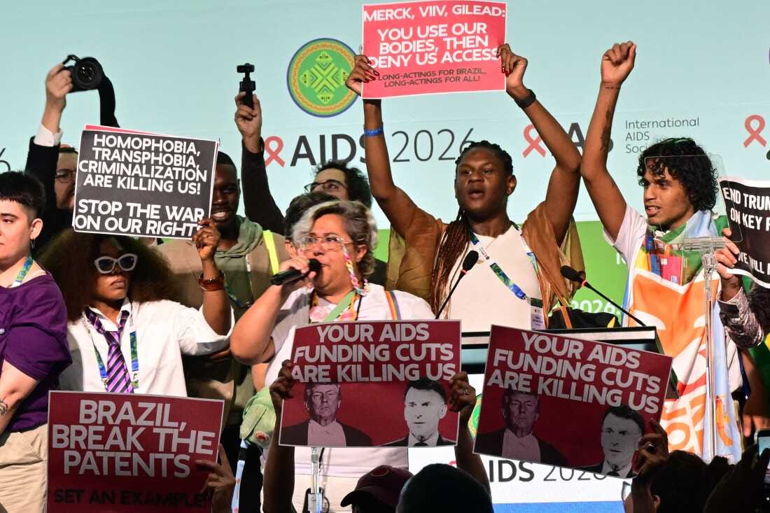 Protesters hold signs, including ones that say "Your AIDS funding cuts are killing us." Protesters hold signs, including ones that say "Your AIDS funding cuts are killing us."