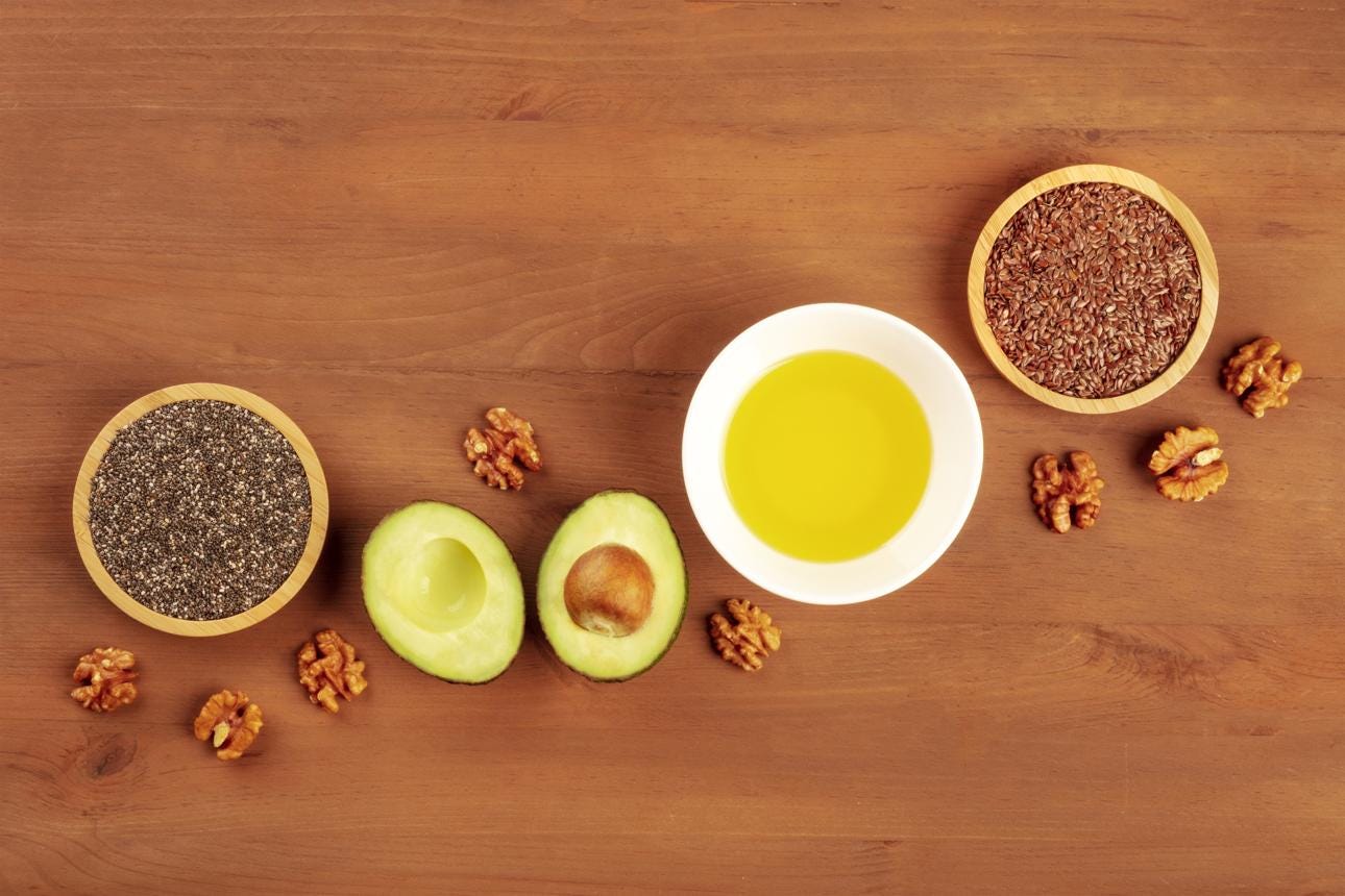Healthy omega 3 vegan diet food products. Avocado, walnuts, chia seeds, flaxseeds, shot from above on a dark rustic wooden background with copy space