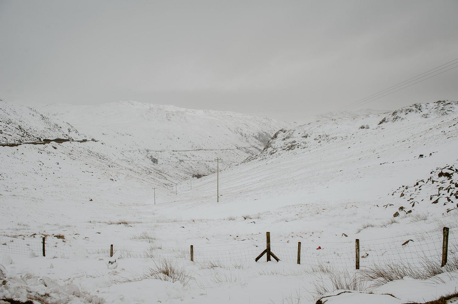 A snow covered landscape with telegraph poles running through the hills.