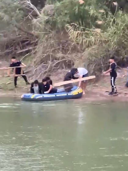 Illegal aliens and smuggling guides prepare to cross the Rio Grande from Mexico into Texas with a makeshift ladder to scale the border wall.