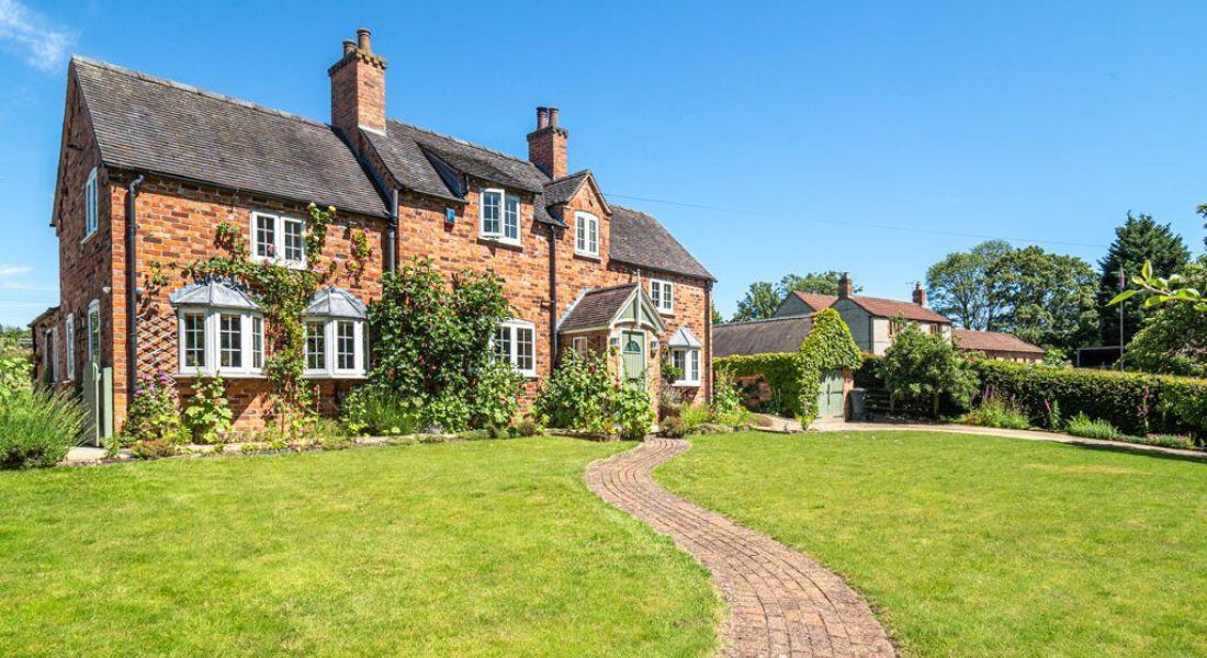 A large brick house with a lawn and winding path in front of it A large brick house with a lawn and winding path in front of it