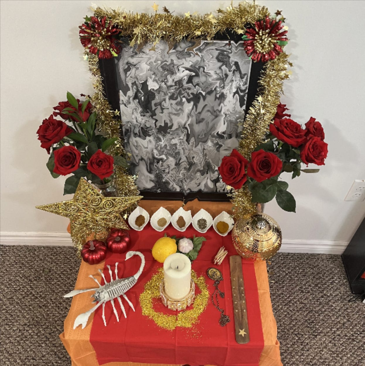 Another altar, this one with red and orange cloth, a scorpion statue, red roses and a golden wreath.