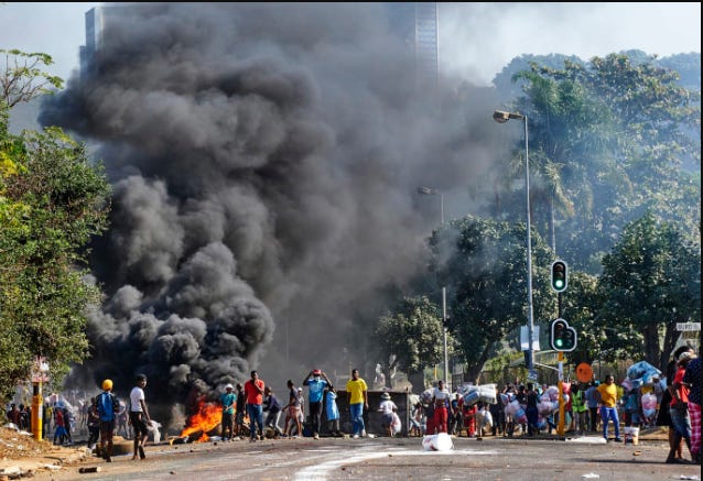 A group of people standing on a street with a large black cloud of smoke

Description automatically generated
