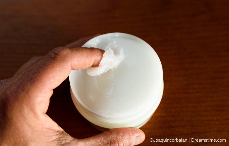 A man picks up white Vaseline to moisturize his skin, dark background A man picks up white Vaseline to moisturize his skin, dark background