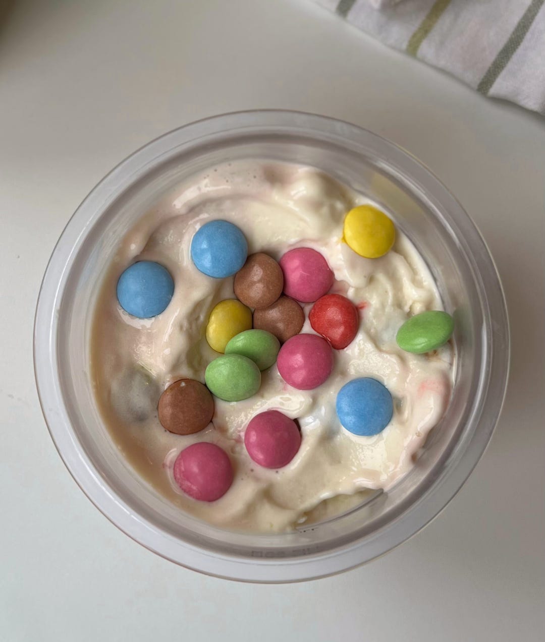 A creamy, high-protein homemade McFlurry topped with colorful chopped smarties, served in a bowl with a spoon."
