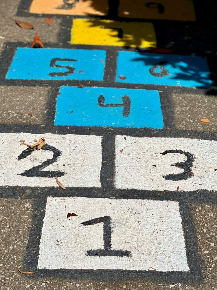 Photo of brightly-painted hopscotch squares on the ground.