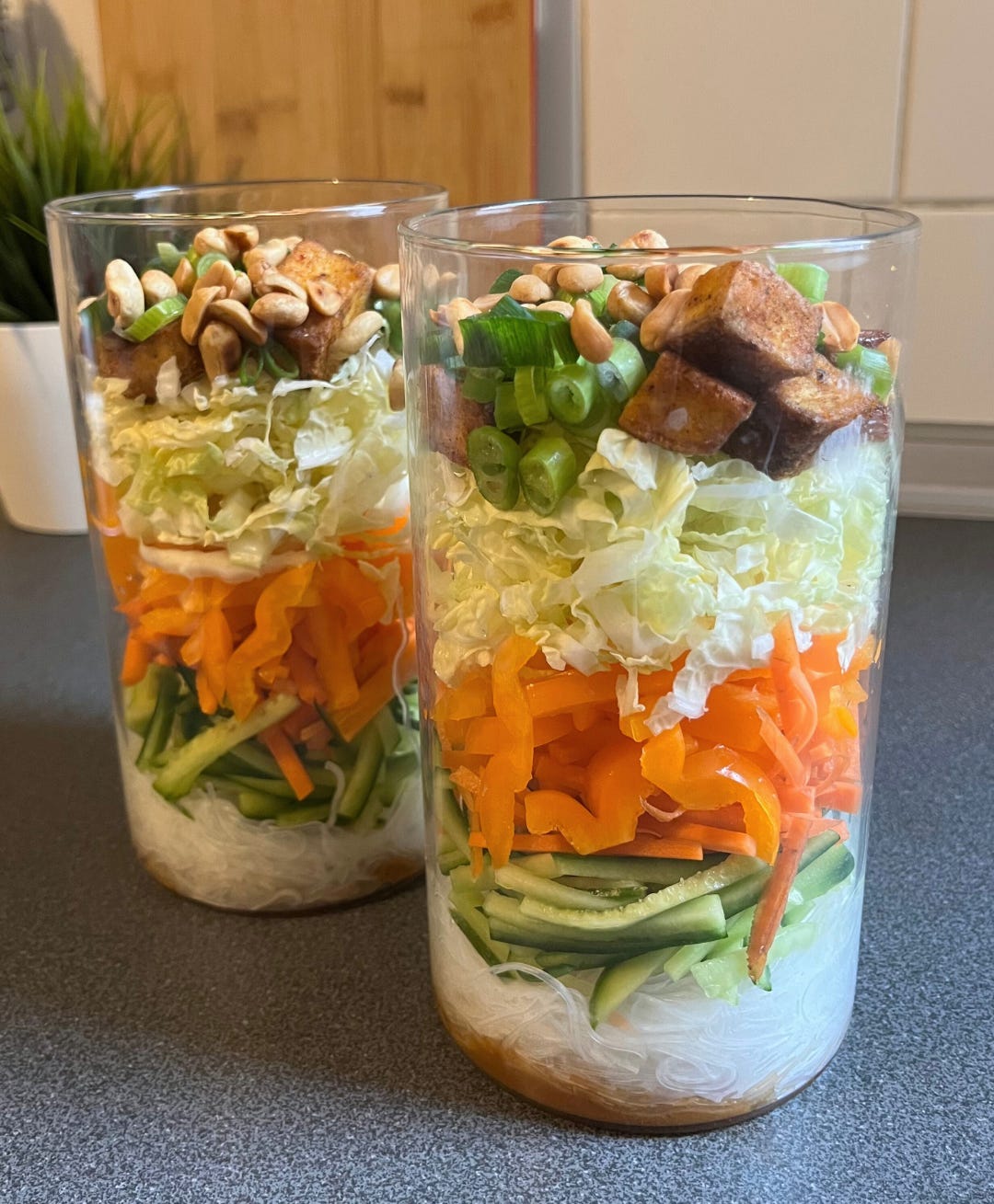 Close-up of a colorful Peanut Noodle Salad Jar layered with rice noodles, bell peppers, cucumber, and crispy tofu
