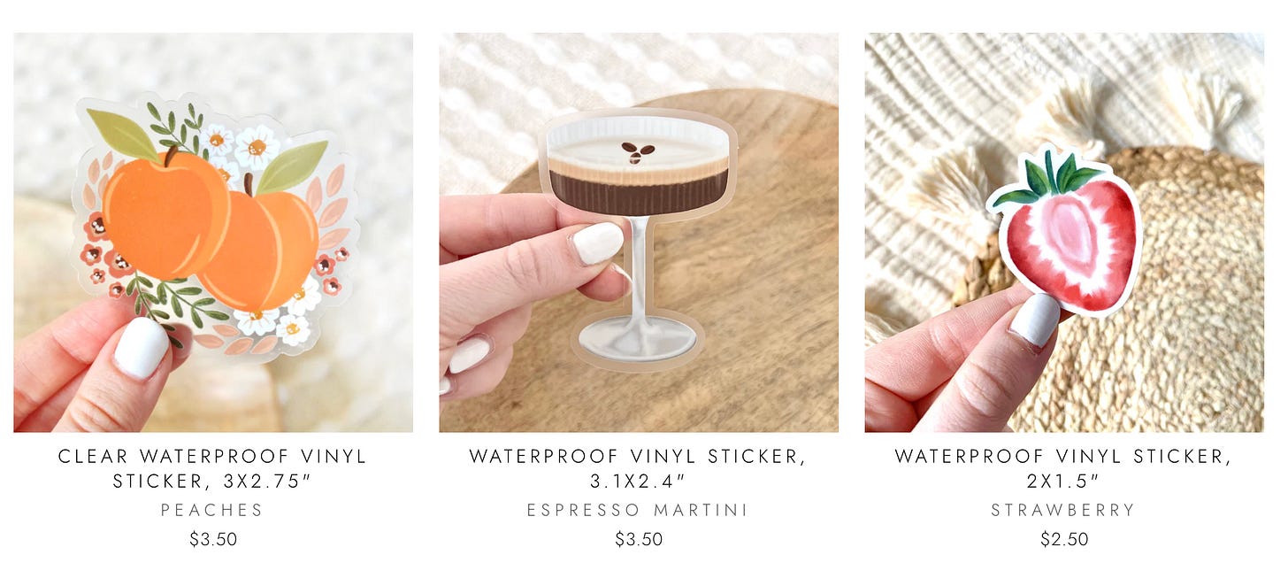 Three vinyl stickers held by hand: peaches with florals ($3.50), espresso martini ($3.50), and strawberry cross-section ($2.50).