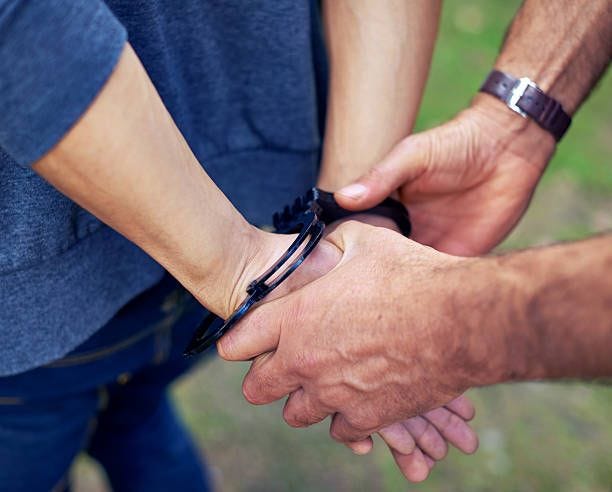 Criminal caught Cropped shot of a policeman's hands putting cuffs on a suspect close up of male in handcuffs behind the back stock pictures, royalty-free photos & images