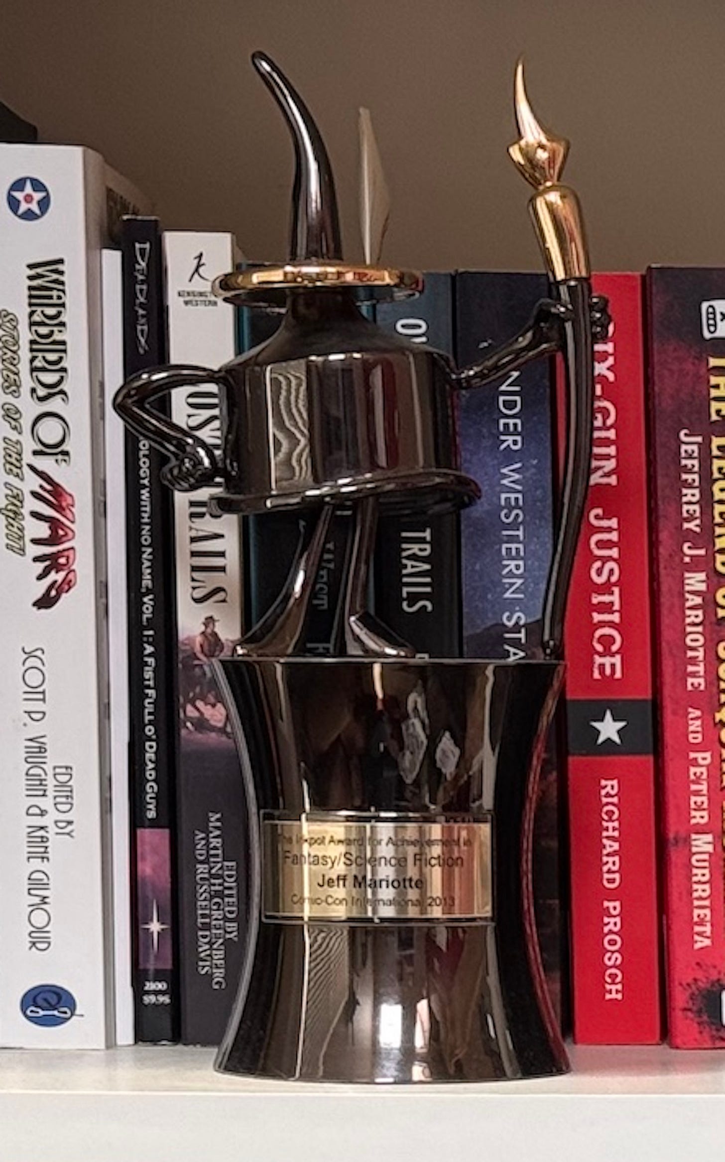 A trophy shaped like an animated inkpot standing and holding a pen