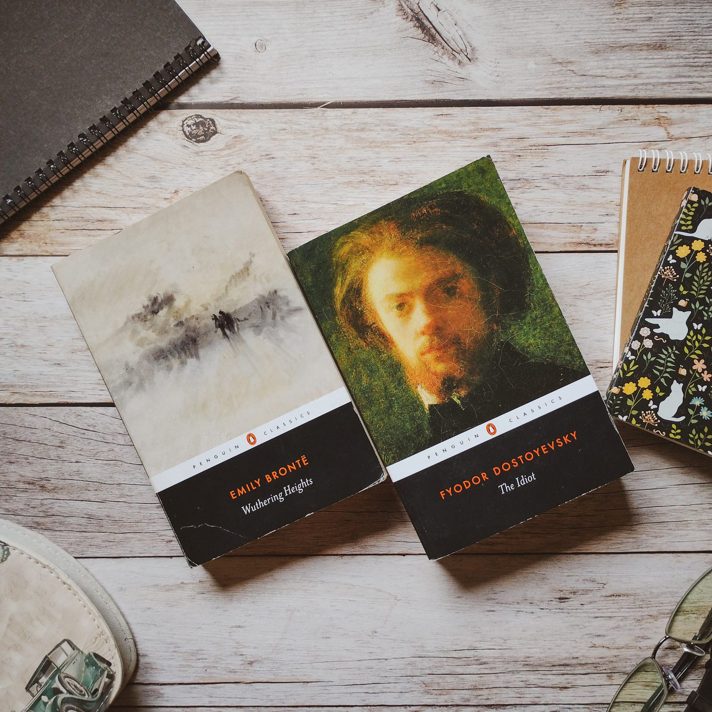 Two books, Wuthering Heights by Emily Brontë and The Idiot by Fyodor Dostoevsky, on a wooden tabletop