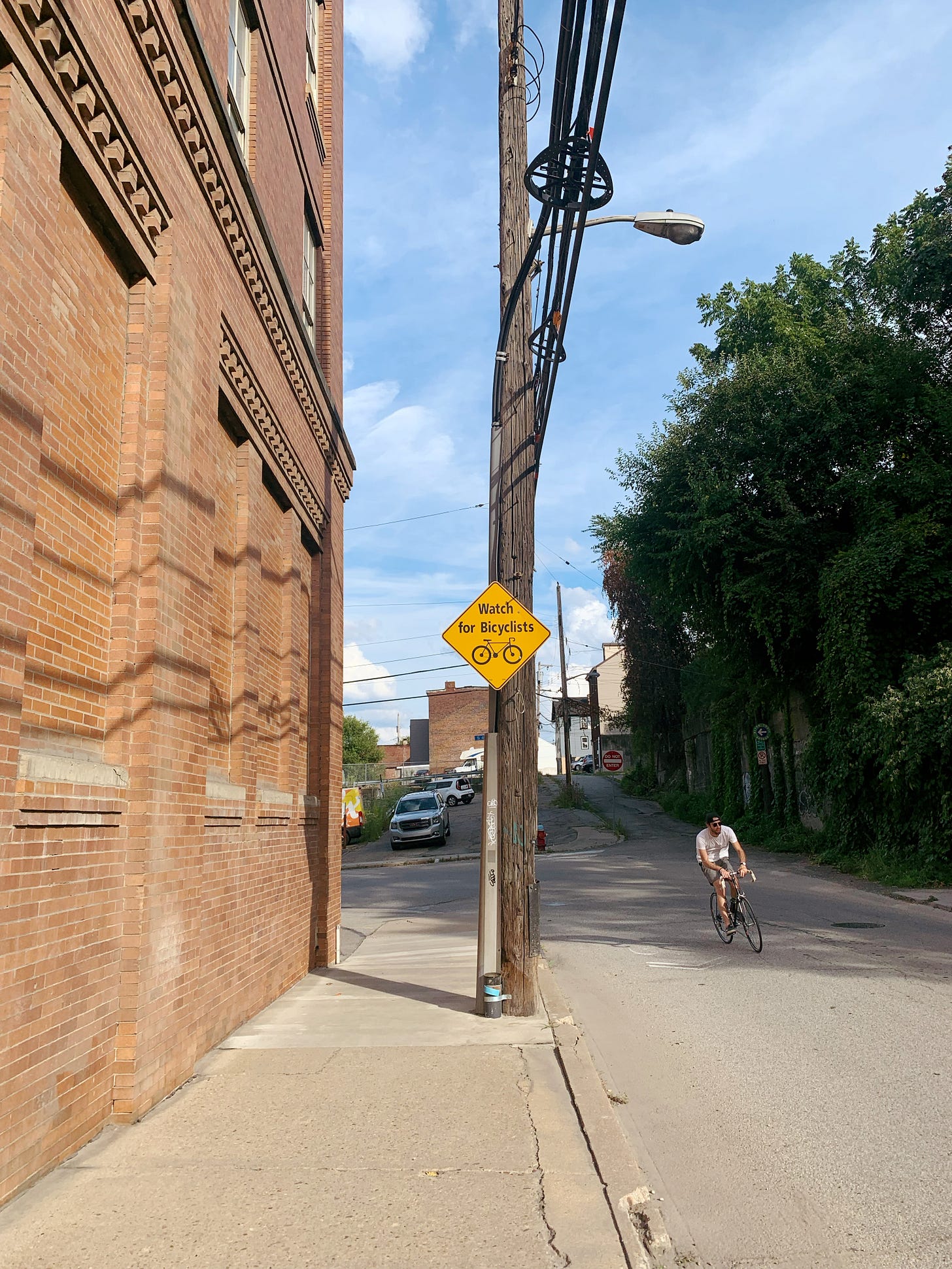 "Watch for Bicyclists" sign and a bicyclist passing by