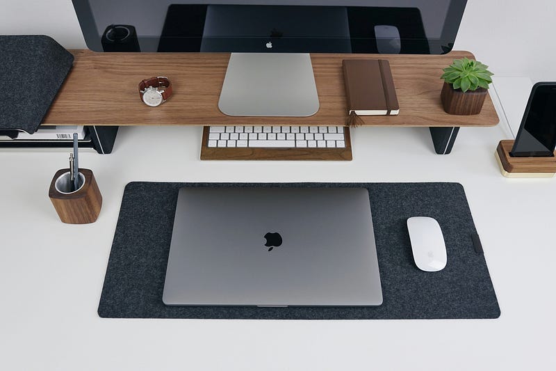 A non cluttered desktop with a Mac, Macbook and an Apple Mouse.