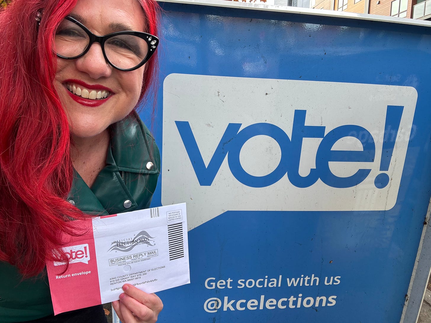 Red-haired middle-aged women with her ballot in front of a voting box.